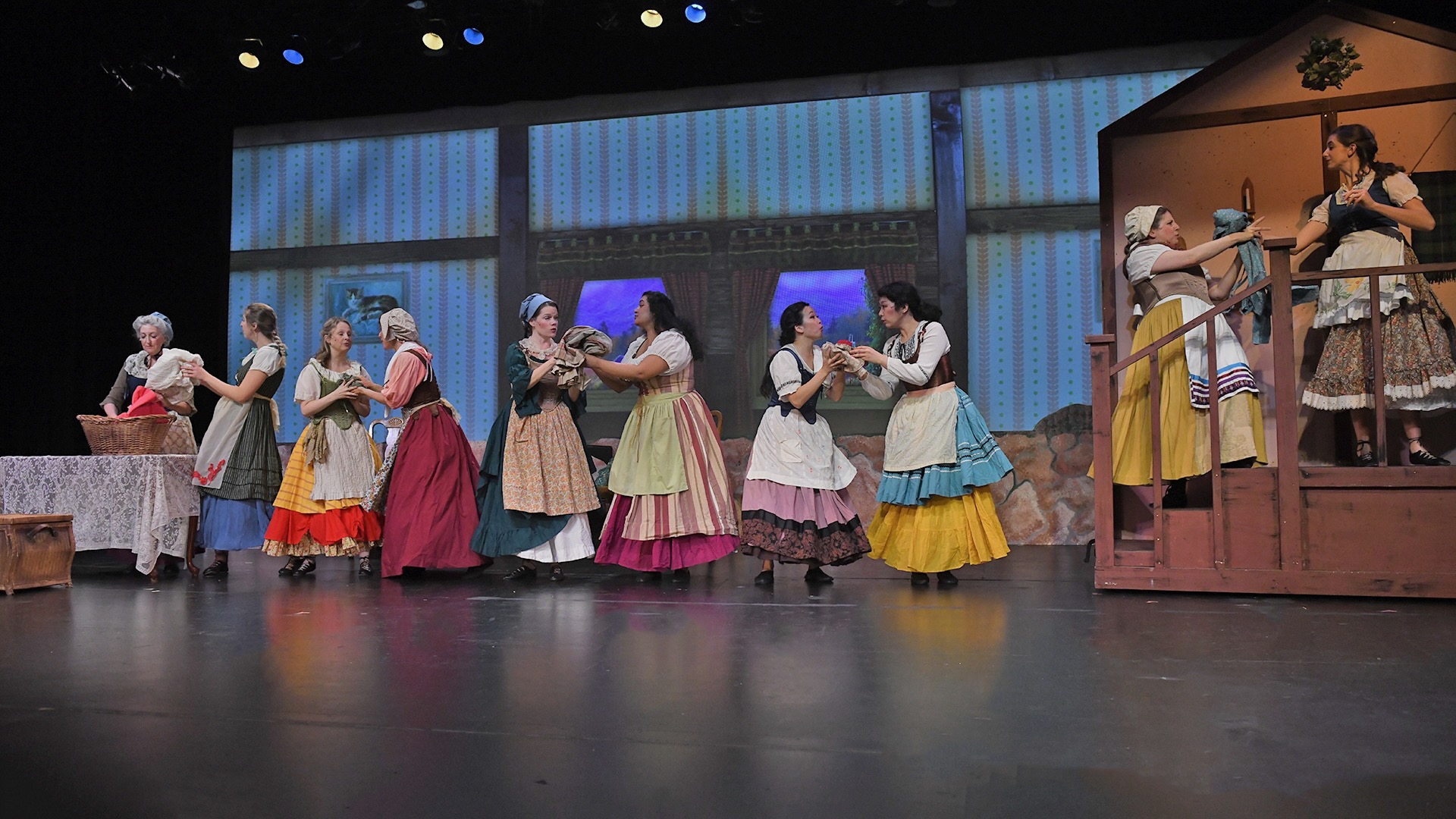 production photo of the house. women stand in a line and pass laundry